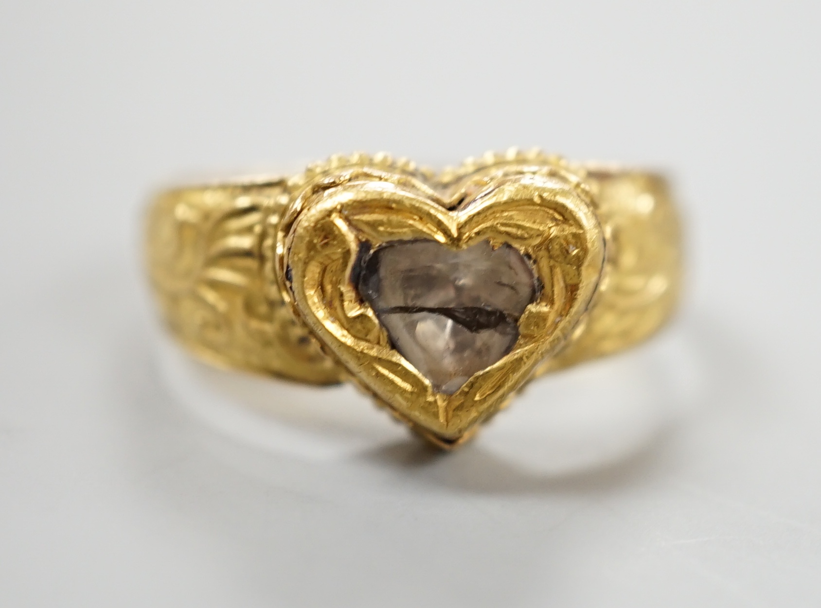An Indian yellow metal and heart shaped diamond set ring, with engraved shank, size O, gross weight 6.2 grams, (crack to stone).